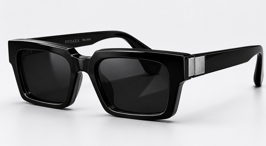 Signature angled view of PYDAXA The Axis architectural sunglasses in Obsidian Black featuring brushed Sterling Silver 925 detailing, sculpted rectangular acetate construction, and luxury cinematic product styling on a clean studio background.